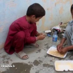 Des enfants afghans pauvres mangent ce que leur donnent les Américains