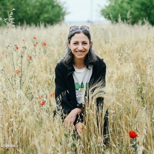 Zeina Shahla pose au milieu d'un champs de pchers et de coquelicots